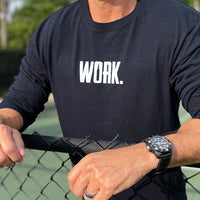 Close up of a man from the front, outdoors, wearing a WW black long sleeve shirt. "WORK." printed on center chest in white ink.