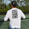 Man outdoors pictured from back wearing a WW white long sleeve shirt. "FAILING IS INEVITABLE—FAILURE IS NOT" printed high on back in black ink [WEWORKIN BRAND APPAREL printed small and lower right just below the word NOT.) Banded cuffs. (Also wearing a backwards WW Black Camo Retro Trucker hat with the WW icon embroidered in white thread on the lower right corner of the right front panel.
