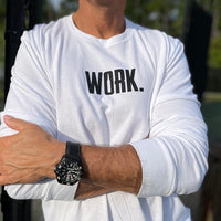 Close up of a man from the front, outdoors, wearing a WW white long sleeve shirt. "WORK." printed on center chest in black ink.