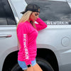 Woman pictured from the side, beside an SUV (with WE WORKIN BRAND transfer decal on back window). She's wearing a WE WORKIN ultralight weight, neon pink long-sleeved tee—center chest imprinted with the text "Not For the Weak" encircling the We Workin WW icon in white ink. WEWORKIN BRAND is printed down the right sleeve in white ink. She's also wearing the We Workin black camo Retro Trucker hat backwards, with white embroidered icon on bottom left front panel.