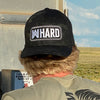 Male wearing a Multicam® Black Flexfit hat backwards. Embroidered with WW HARD "patch" style across the front (WW HARD icon/text in white thread, outer outline in white thread, inner outline in gray thread). 